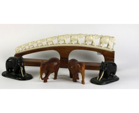 A collection of carved model Elephants, including an early 19th Century ivory elephant bridge, together with a pair of ebony 