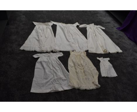 A selection of antique items of baby clothing including one long gown with cut work and embroidered hem, tie sash to waist an