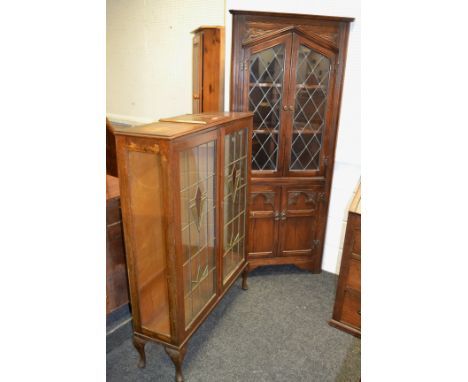 A Jacobean Revival Oak astral glazed corner unit enclosing two shaped shelves above two covered doors; an Art Deco oak staine