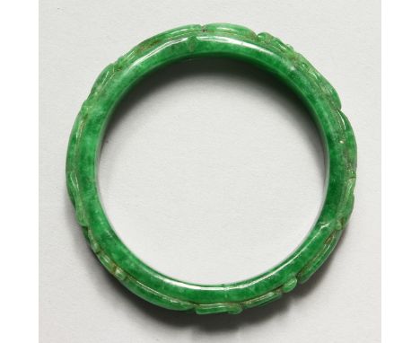 A CHINESE CARVED APPLE GREEN JADE BANGLE. 2.75ins diameter.