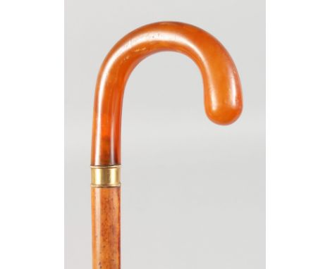A GOOD AMBER HANDLED WALKING STICK with gold band. 36ins long.