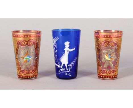 A SMALL PAIR OF RUBY GILT BEAKERS, encrusted with birds, 3ins high, and A MARY GREGORY BLUE BEAKER, 3.75ins high (3).