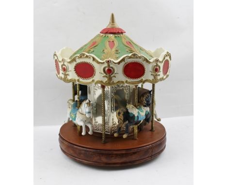 A "MELODY IN MOTION" JAPANESE MUSICAL CAROUSEL, mounted with four ceramic fairground horses, battery operated, with instructi
