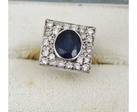 AN 18CT GOLD ART DECO STYLE SAPPHIRE AND DIAMOND RING, the central oval sapphire set within a square of mixed size diamonds, 