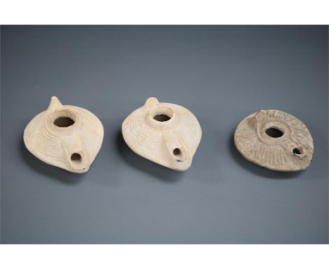 Byzantine Oil Lamp Group, 5th-6th century AD A group of three ceramic oil lamps, two with pale buff oval bodies, the spout fo