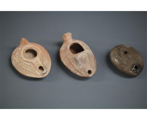 Byzantine Oil Lamp Group, 5th-6th century AD A group of three ceramic oil lamps with oval bodies, the nozzle integral to the 