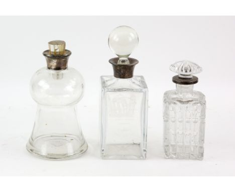 Three silver-mounted glass decanters including a thistle-shaped decanter, 23 cm high, a oblong decanter with acid-etched deco