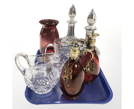 A group of crystal decanters, glass jugs, a pair of ruby tinted glass antique decanters with labels.