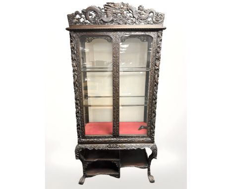 A 19th century Chinese heavily-carved hardwood double door glazed display cabinet, width 99 cm, height including carved pedim