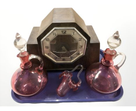 An Art Deco oak cased mantel clock, together with a pair of cranberry glass decanters and a basket.