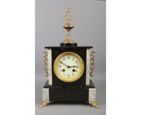 An ornate French slate 8 day mantel clock with brass mount decoration, raised on four brass claw feet. (39cm)  Pendulum prese