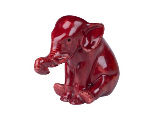 A rare Bernard Moore flambe-glazed porcelain figurine depicting a seated elephant with a charming and expressive pose. The de