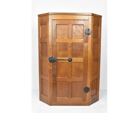 Robert 'Mouseman' Thompson (1876-1955) An oak hanging corner cupboard, circa 1955, with panelled door enclosing fixed shelves