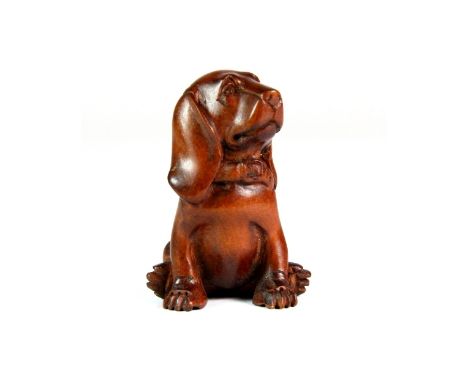 A carved fruitwood netsuke of a dog