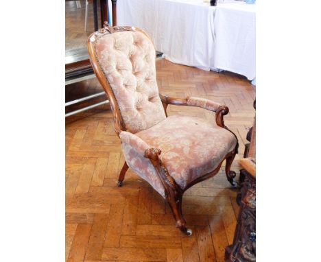 A Victorian carved walnut frame armchair, with foliate carving, button back, padded arms and upholstered seat, on cabriole le