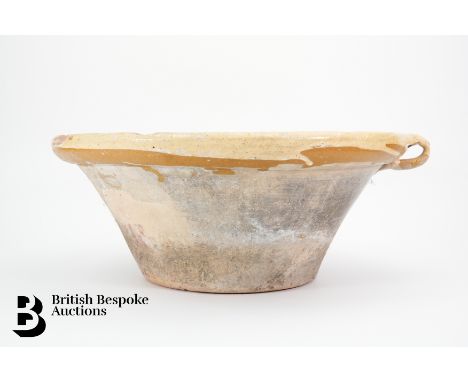 A large terracotta dairy bowl with light yellow glaze to inside, measures approx. 42 x 17 cms. (af)