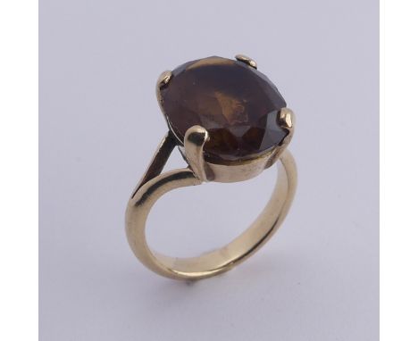 A smoky quartz Dress Ring, the oval facetted stone 16mm long, four claw set in unmarked gold, tested as 9ct, Size M, total we