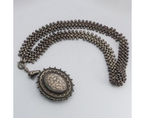 A Victorian Aesthetic movement silver Locket, of oval form with foliate decoration and monogrammed reverse, on a typical neck