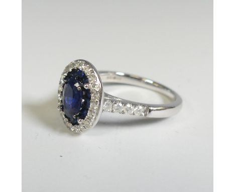 A sapphire and diamond Cluster Ring, the central oval facetted sapphire, approx. 7mm long four claw set above a surround of t