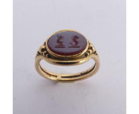 An 18ct yellow gold Signet Ring, the front set with an oval carnelian, carved with two mythical beasts, the stone 9.3mm wide,