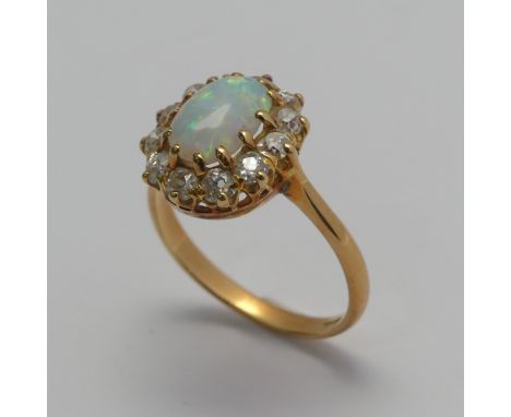 An opal and diamond cluster Ring, the central oval cabochon opal, approx. 8.8mm long, claw set within a surround of twelve sm