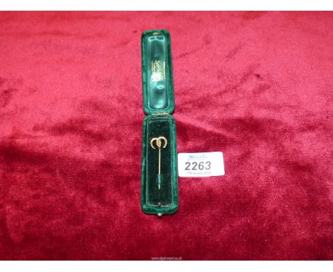 A yellow metal horseshoe stick pin in green velvet case.