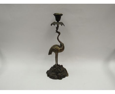 A bronzed candlestick in the form of a heron standing on rocky outcrop, 40cm tall