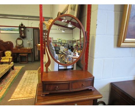 A George III style mahogany bow front dressing chest tilting oval mirror on a two drawer base and ogee bracket feet