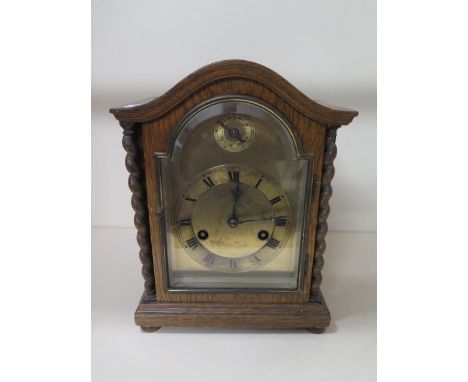 An oak mantle clock striking on a gong with key, 25cm tall, front door hinge broken, runs but stops 