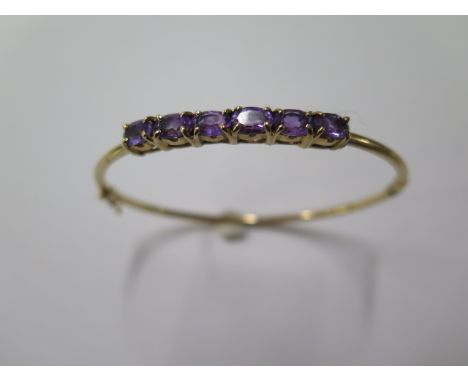 A 9ct yellow gold hinged amethyst bangle, 7.5cm x 6.5cm, approx 7.3 grams, in good condition 