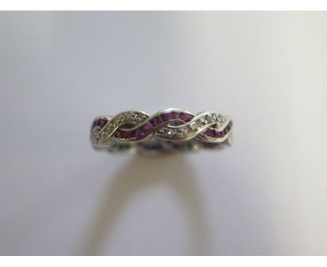 A platinum ruby and diamond ring of plaited design with one strand of channel set calibre cut rubies and one string of gram s