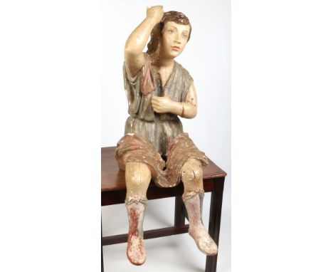 A 19th century Venetian carved wood, gesso and polychrome figure of a seated boy. Modelled holding a pole, this now lacking, 