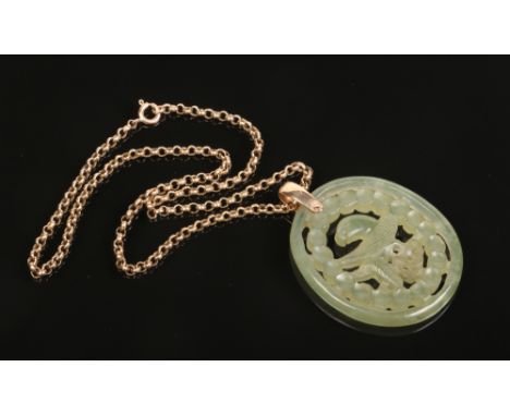 A carved and pierced jade amulet depicting a parrot and supported on a 9 carat gold rolo chain. Jade 52mm x44mm.Condition rep