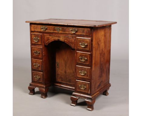 An early Georgian kneehole walnut desk. With strung inlay, original brightwork and raised on ogee bracket feet, 84cm wide, 48