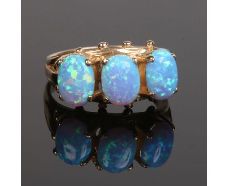 A 9 carat gold three stone opal ring. With split shoulders and claw set with three large ovoid stones approximately 8mm x 6mm