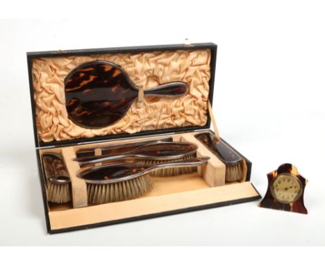 A George V cased six part silver and tortoiseshell dressing table set and associated Swiss strut clock. Assayed London 1926, 