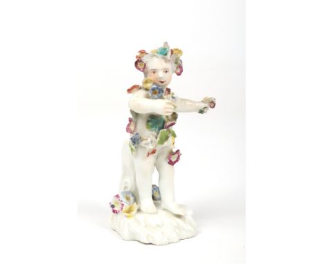A Derby pale period figure of a putto. Wearing a flower wreath, a garland and holding flowers. Patch marks and incised marks 