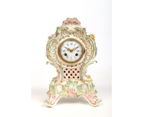 A 19th century china cased mantel clock in the Rococo style. Moulded with shells and scrollwork edged in turquoise and pink a