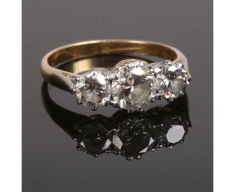 A gold three stone diamond ring set with round cut diamonds. The centre stone approximately 0.7ct flanked by a pair at approx