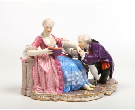 A 20th century Nymphenburg figure group 'the Kiss' formed as a couple in courtly attire, the female figure reading a book whi