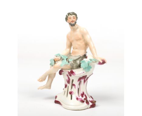 A Vienna figure of a man coloured in enamels. Dressed in a loin cloth holding a leafy garland and raised on a Rococo style pi