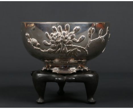 An early 20th century Chinese heavy gauge silver bowl on associated hardwood stand. Decorated in raised relief with two peony