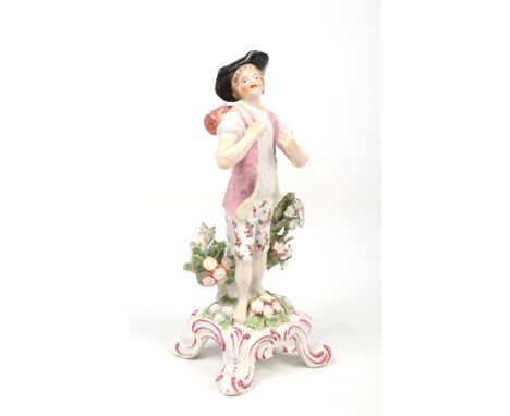 A rare Bow figure of a boy carrying a barrel over his shoulder on a strap. Coloured in enamels and raised on a Rococo style f