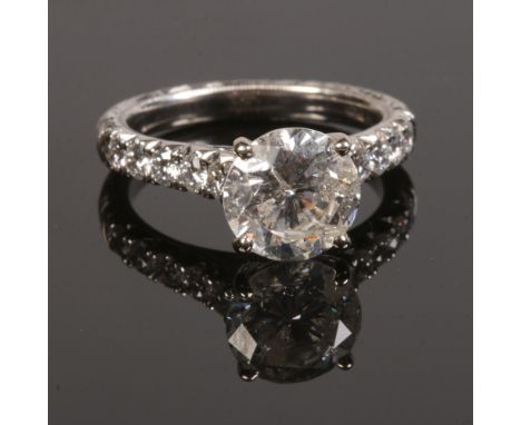 A 14 carat white gold and diamond ring. Set with a large brilliant cut diamond approximately 3ct on a feather engraved shank 