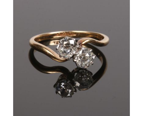 A mid 20th century 18 carat gold and platinum two stone diamond crossover ring. Set with a pair of old European cut diamonds 