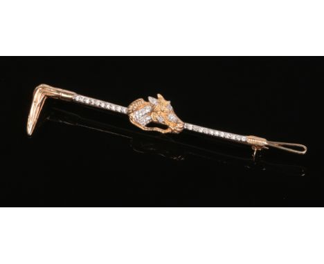 A 9 carat gold equestrian themed bar brooch. Formed as a riding crop, surmounted as a horses head and studded with diamonds. 