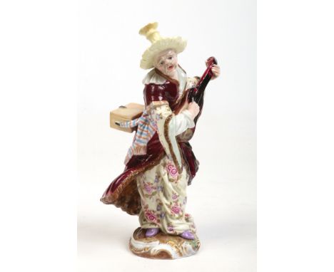 A 19th century Meissen figure of a Malabar musician. Modelled in a standing pose playing a stringed instrument with a tall br