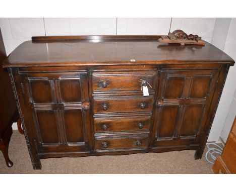 An Ercol dark stained side cabinet, fitted four drawers flanked by cupboard doors, 144cms wide.