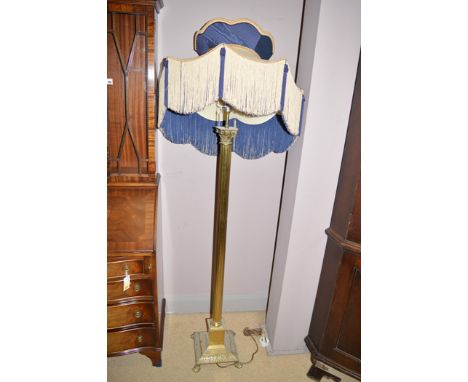 A 20th Century brass standard lamp, Corinthian style column with blue and cream tasselled shade.