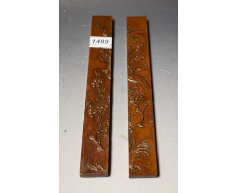 A pair of Chinese style bronze scroll weights, cast in low relief with birds amongst flowering prunus branches, 24cm long (2)